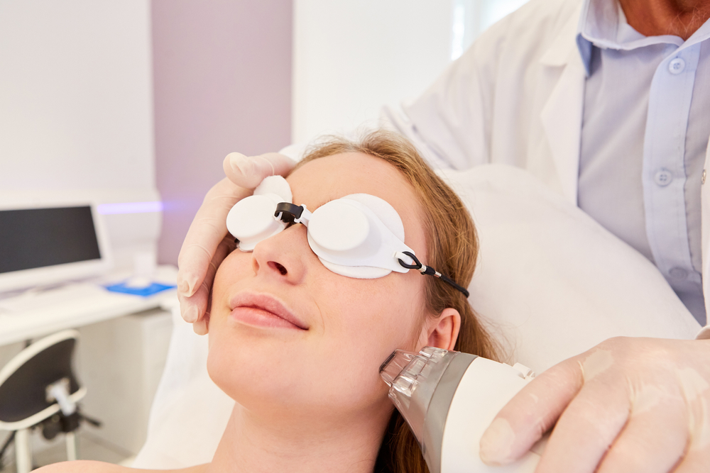 Patient undergoing Fraxel laser treatment for acne scars, wearing protective eye gear in a clinical setting.